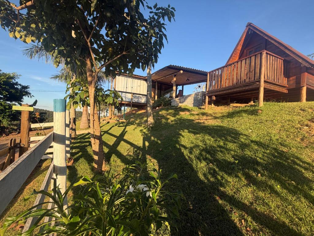 a house on a hill with a tree in the foreground at Chalé e Cabana Taubate in Taubaté
