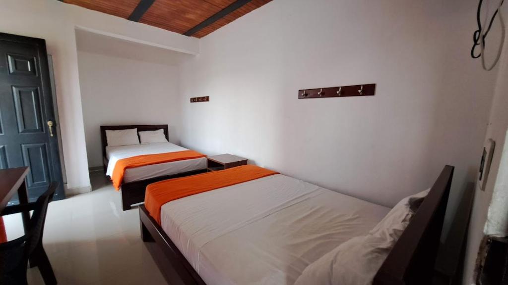 a room with two beds and a table and a door at Hotel Rios in Garzón