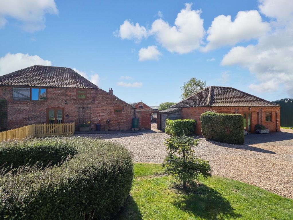 two brick buildings with bushes in a yard at Barn Owl in Louth