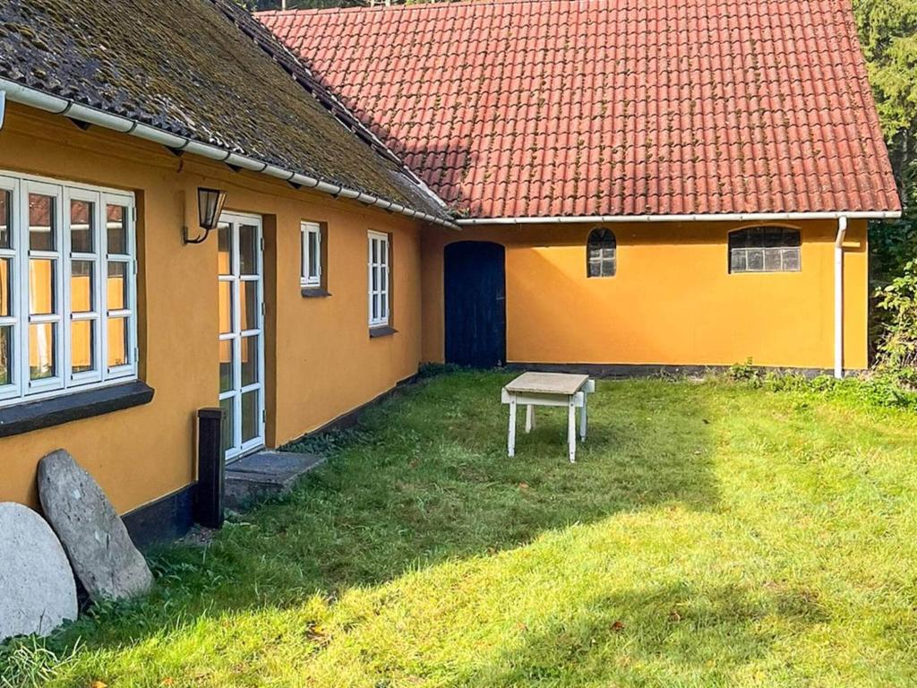 a yellow house with a bench in front of it at Lakeside Holiday Home with Forest in Skanderborg