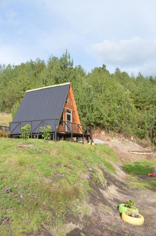 a log cabin with a black roof on a field at Tierra Viva By Astrid in Cucunubá