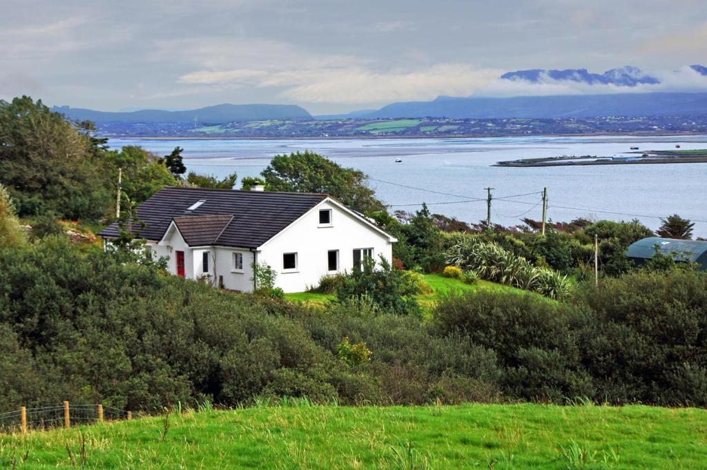 a white house on top of a hill with the water at 3 Bed in Inch oc-i444 in Caheracruttera