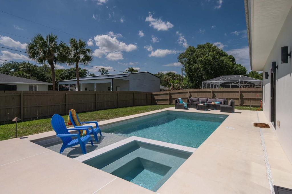 a swimming pool with two blue chairs next to a yard at Spacious home private pool patio & bbq in Vero Beach