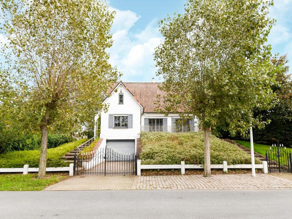 a white house with a fence and trees at Floribert in Nieuwpoort-Bad