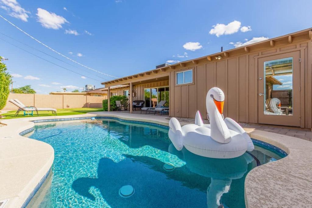 a swimming pool with an inflatable swan in front of a house at Games Galore - Old Town Scottsdale - Pool & Golf in Scottsdale