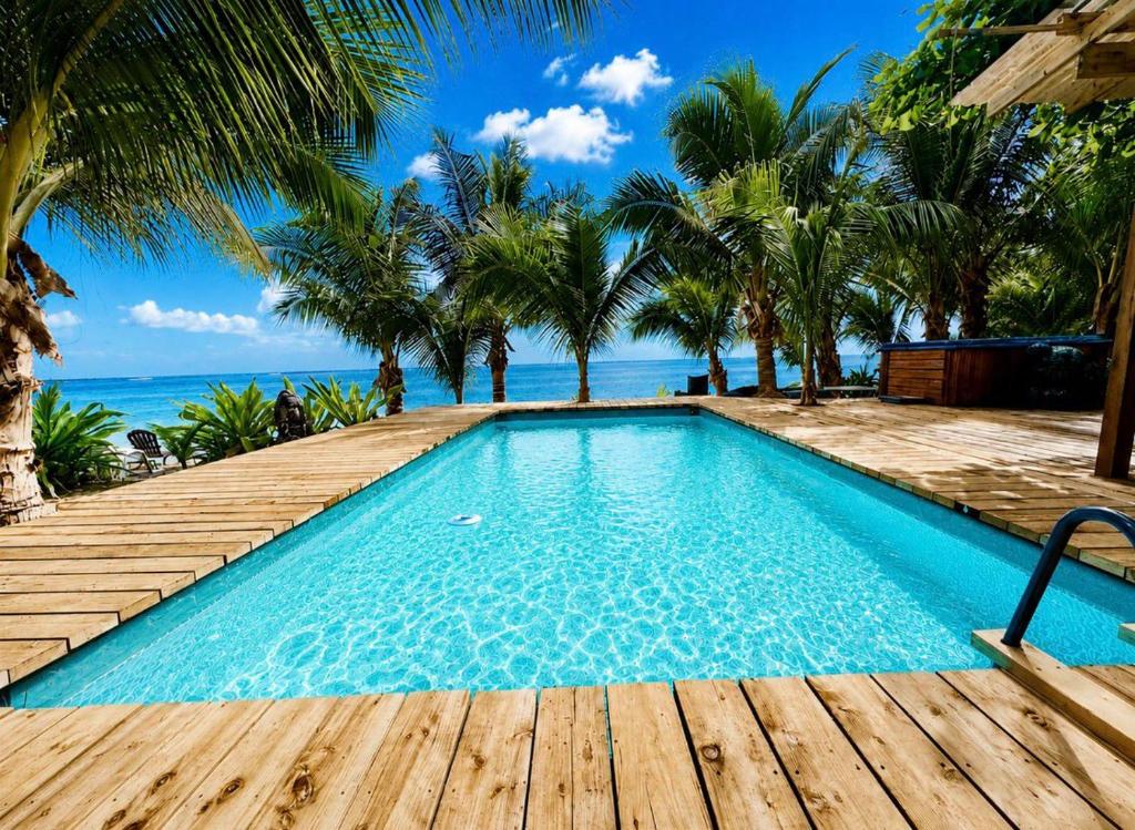 a swimming pool with a wooden deck and the ocean at Fare Oaoa Haapiti in Moorea