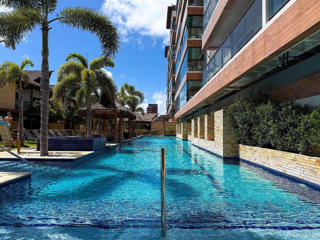 a swimming pool next to a building with palm trees at Villas de Samoa - House with 4 bedrooms in Cabedelo