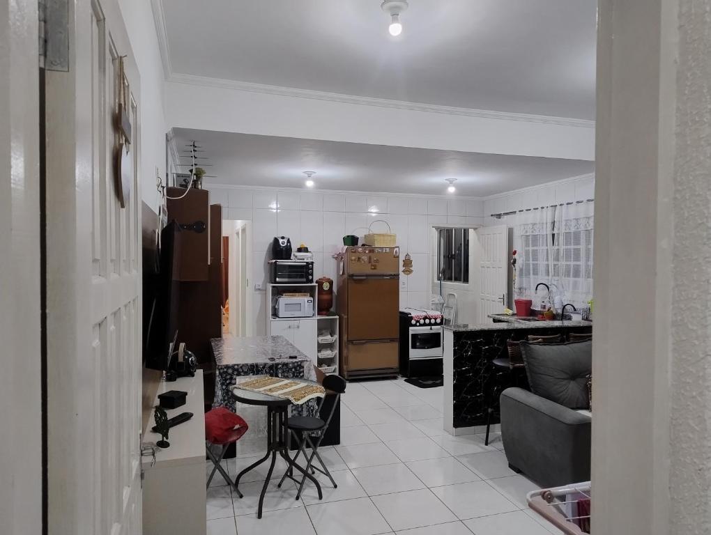 a kitchen and living room with a couch and a table at Casa aconchegante in Peruíbe