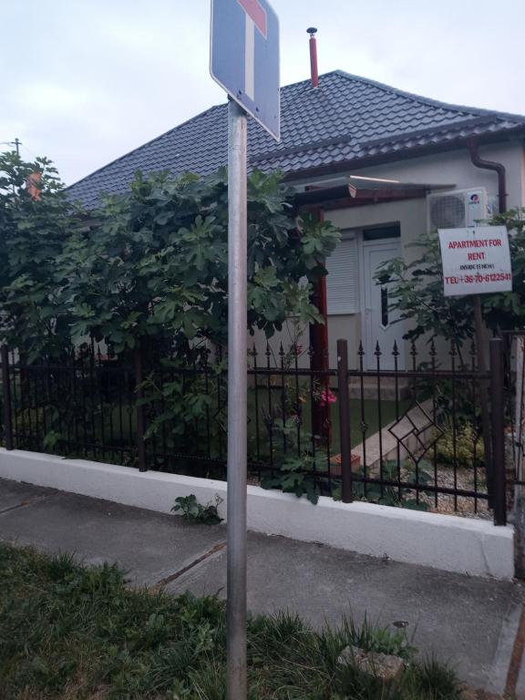 a sign in front of a house with a fence at Adam Apartman in Hajdúszoboszló