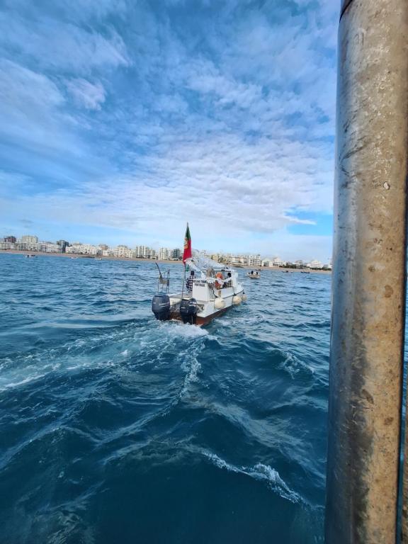 a small boat with a flag in the water at Maré Viva in Quarteira