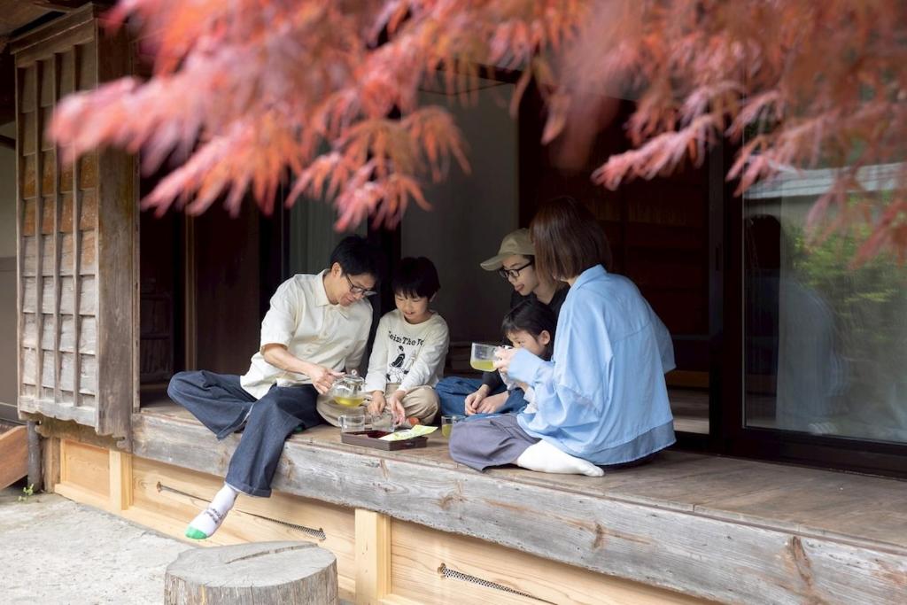 a group of people sitting on a wooden bench at Nagi no Ne in Washika