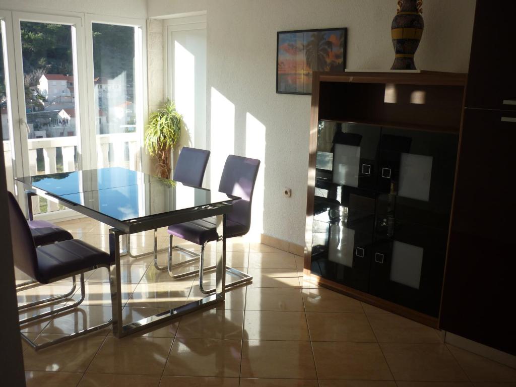 a dining room with a glass table and chairs at Apartments Nikola in Pučišća
