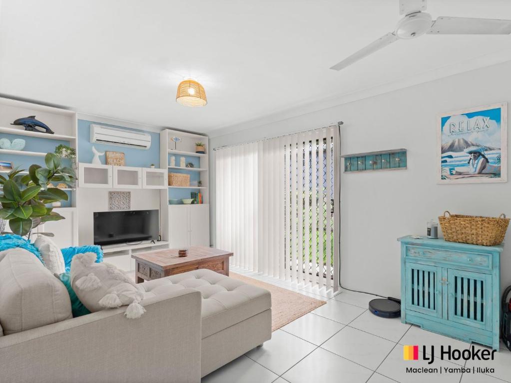a living room with a couch and a tv at Barefoot by the Bay in Iluka