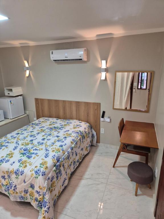 a bedroom with a bed and a desk and a window at Suíte Praia Seca com ar condicionado in Araruama