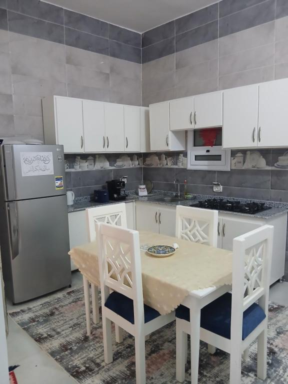a kitchen with a table and white cabinets and a refrigerator at Sunny said gust house in Al Aqālitah
