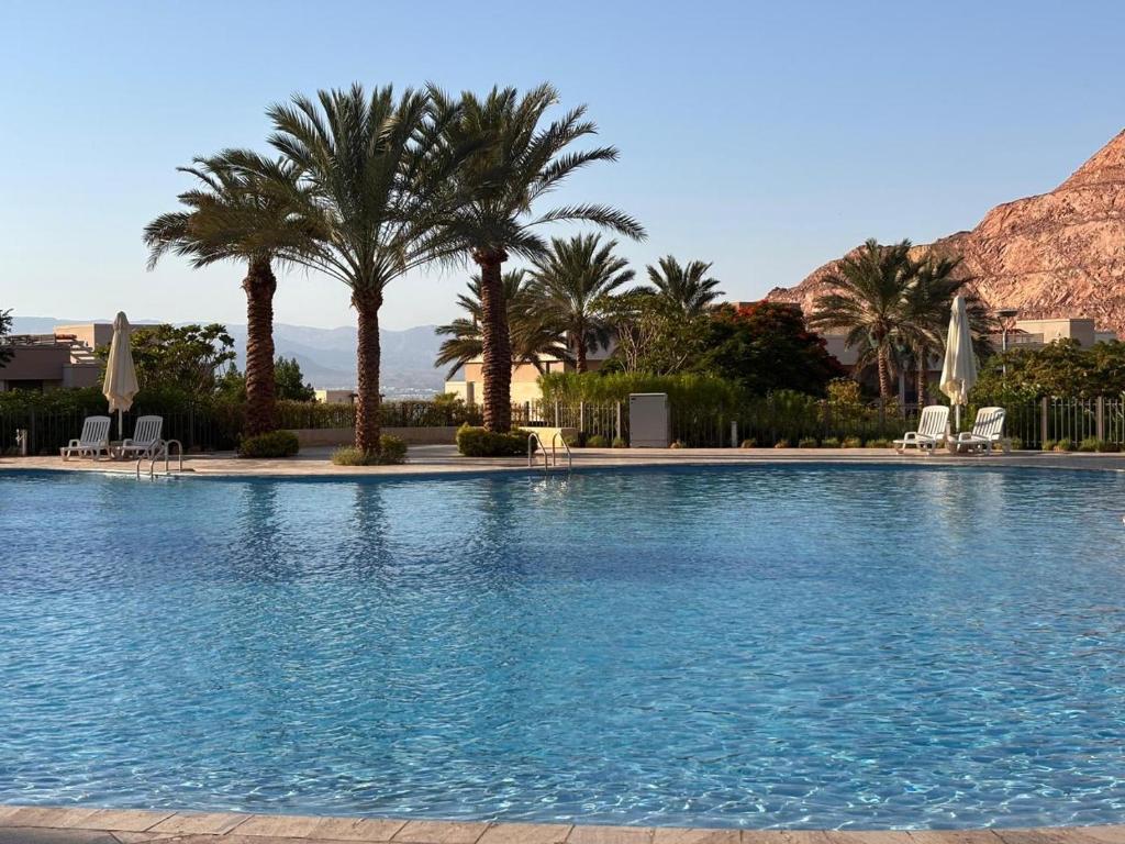 a large swimming pool with palm trees and umbrellas at Raha Inn Apartment in Aqaba