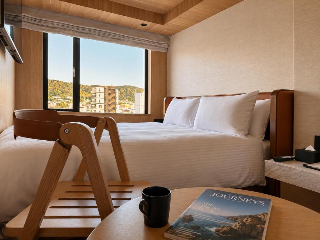 a hotel room with a bed and a book on a table at KIORI Hotel Teramachi in Kyoto