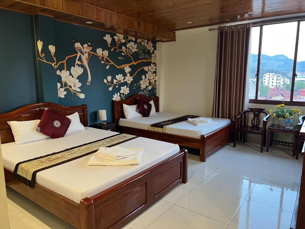 a hotel room with two beds and a window at Ngan Nga in Bắc Hà