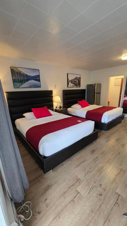 two beds with red and white sheets in a room at Mountain View Hope Motel in Hope