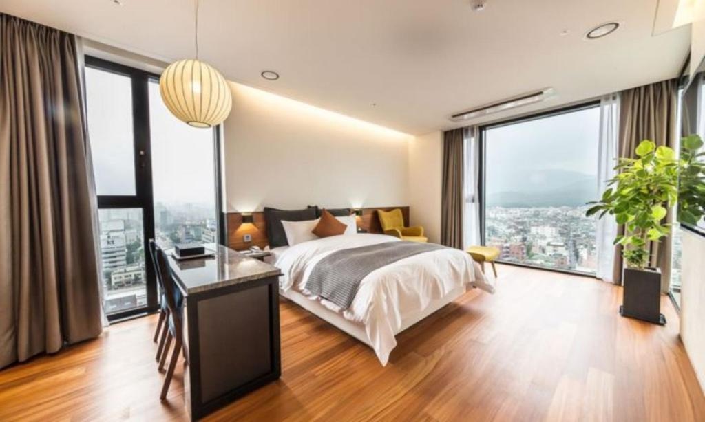 a bedroom with a bed and a desk and large windows at Dobong Hotel Bay204 in Seoul