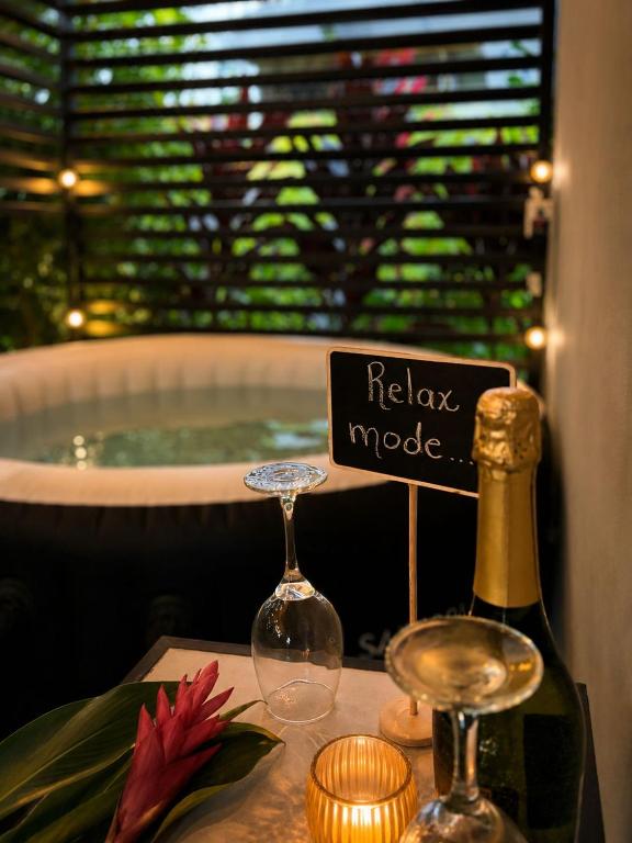 a bottle of wine and glasses on a table with a bath tub at The Slothie's House in Fortuna