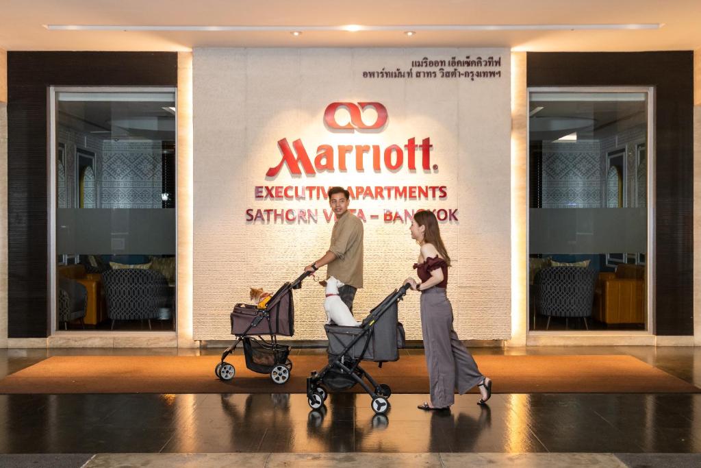 A family with two strollers passes the hotel’s Executive Apartments entrance.