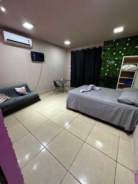 a room with a bed and a tv and a table at Quarto próximo ao parque de exposição BR163 in Dourados