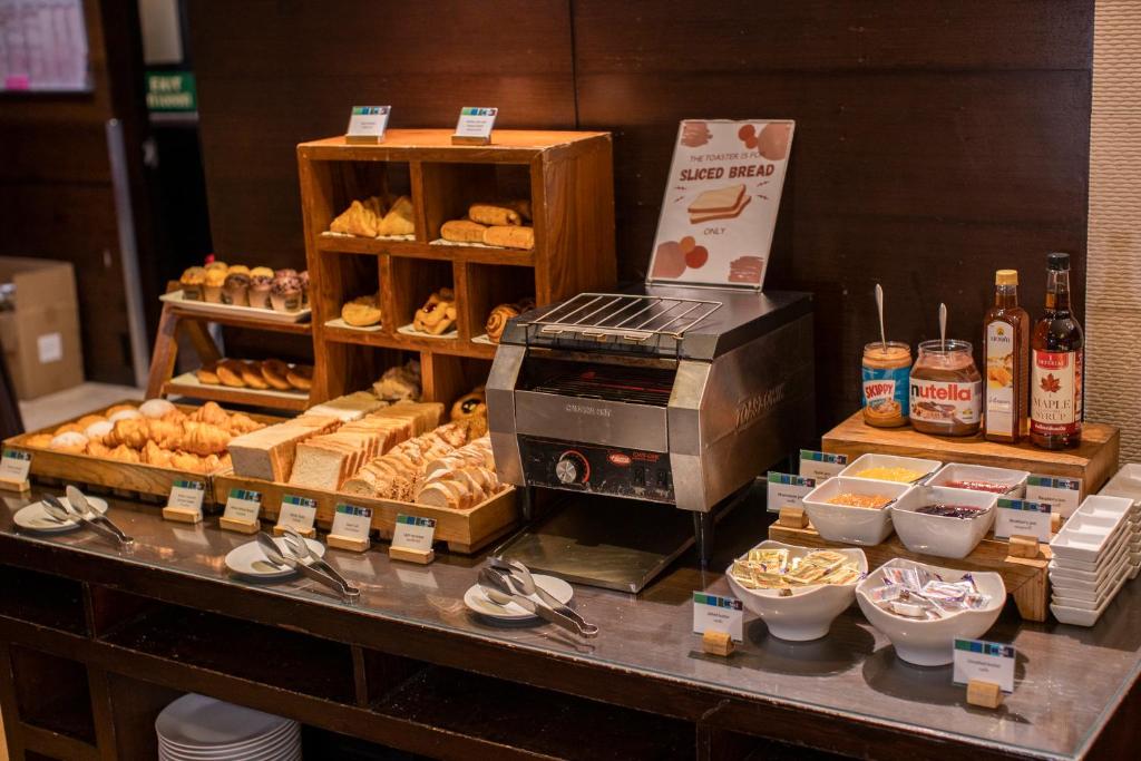 A bakery-style breakfast counter stocked with breads, pastries, spreads and yoghurt toppings.