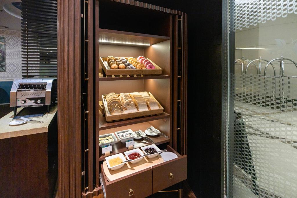 A pastry and breakfast display with croissants, macarons, bread and condiments.
