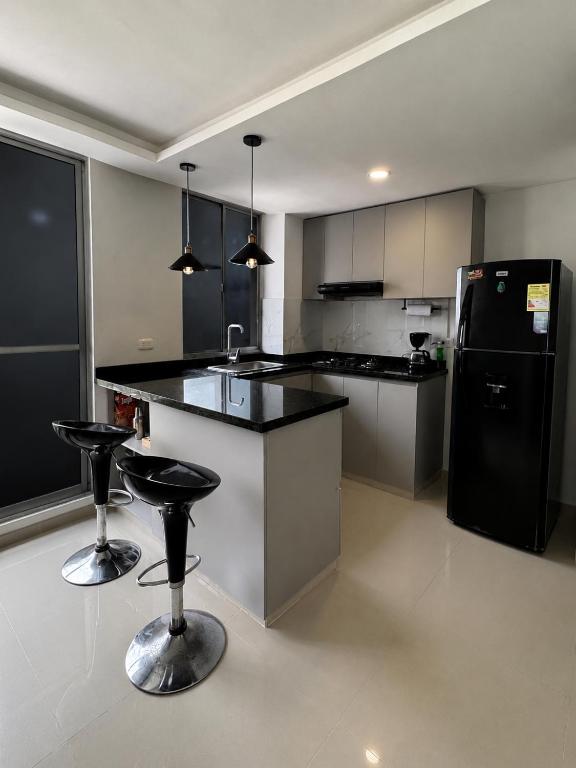a kitchen with a black refrigerator and two bar stools at Barranquilla Prime Apartment in Barranquilla