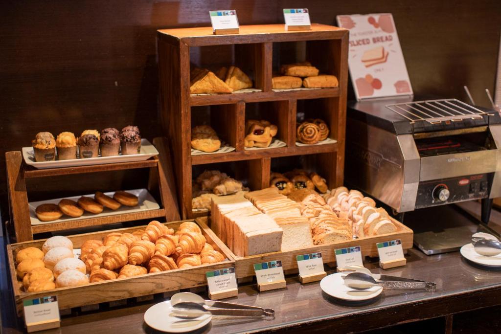 A pastry display filled with croissants, doughnuts, rolls and sliced bread.