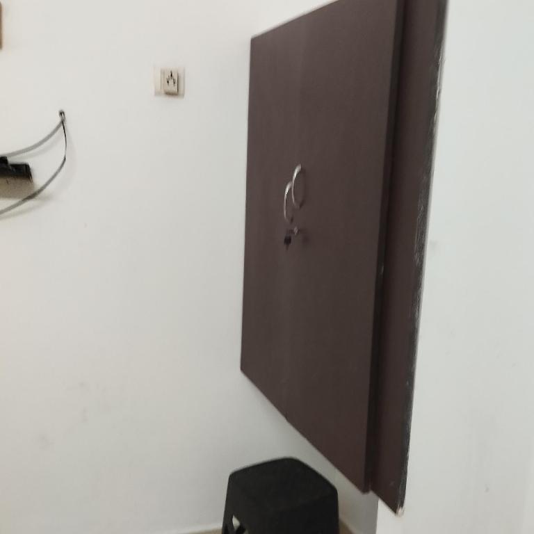 a door on a white wall with a black stool at Shifa Home Near Apollo Sankara Nethralaya Main Hospital in Chennai