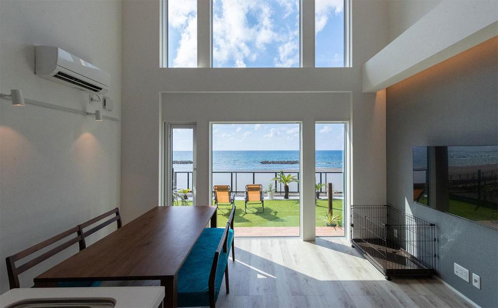 a dining room with a table and a view of the ocean at Tabinoteitaku Y-beach in Tsuruoka