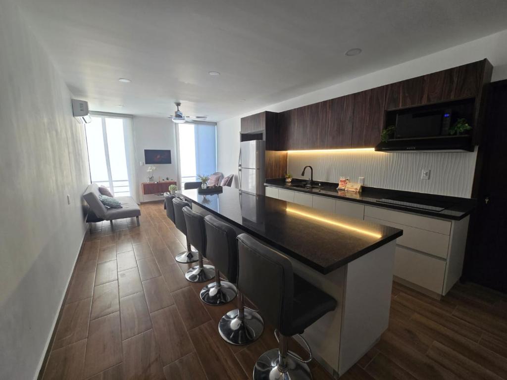 a kitchen with a counter and a bar with stools at hermoso departamento totalmente equipado ,céntrico, aberca, elevador , estacionamiento privado in Mazatlán