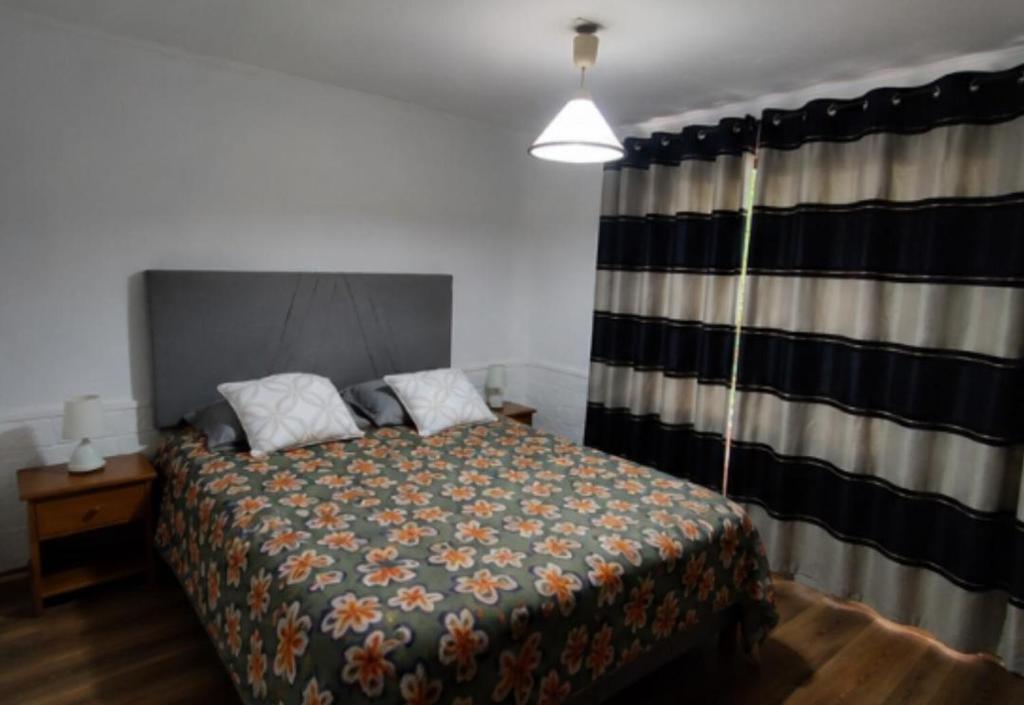 a bedroom with a bed and a window with a curtain at Estrella rooms La Florida in Santiago