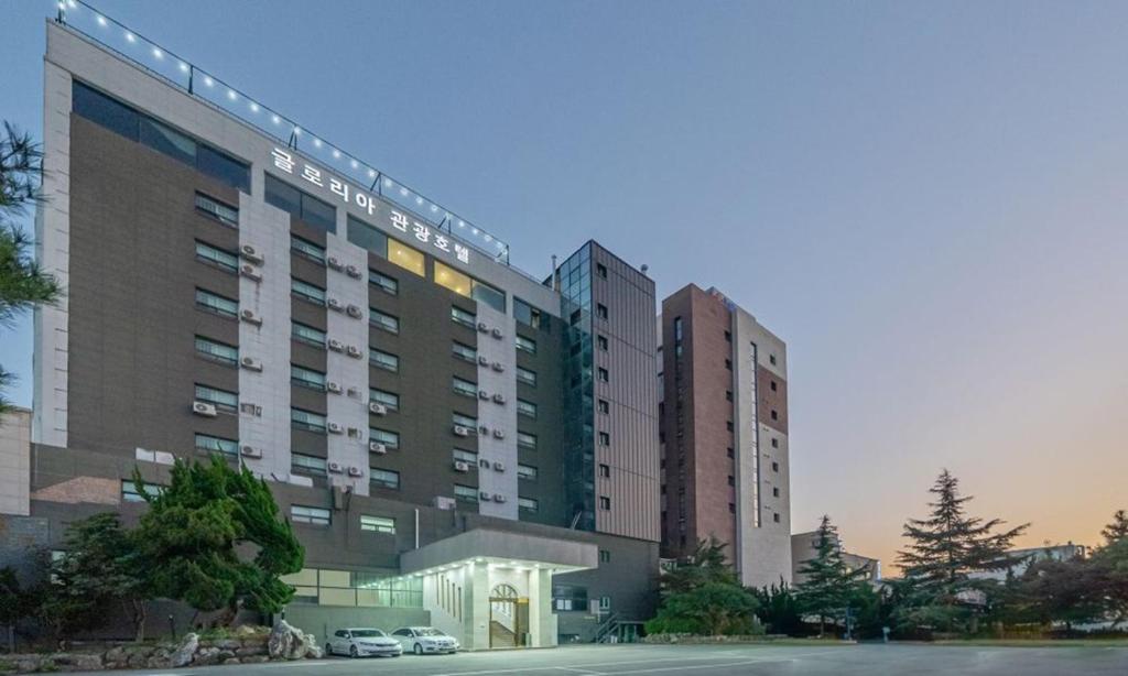 two tall buildings with a car parked in a parking lot at Donghae Gloria Hotel in Donghae