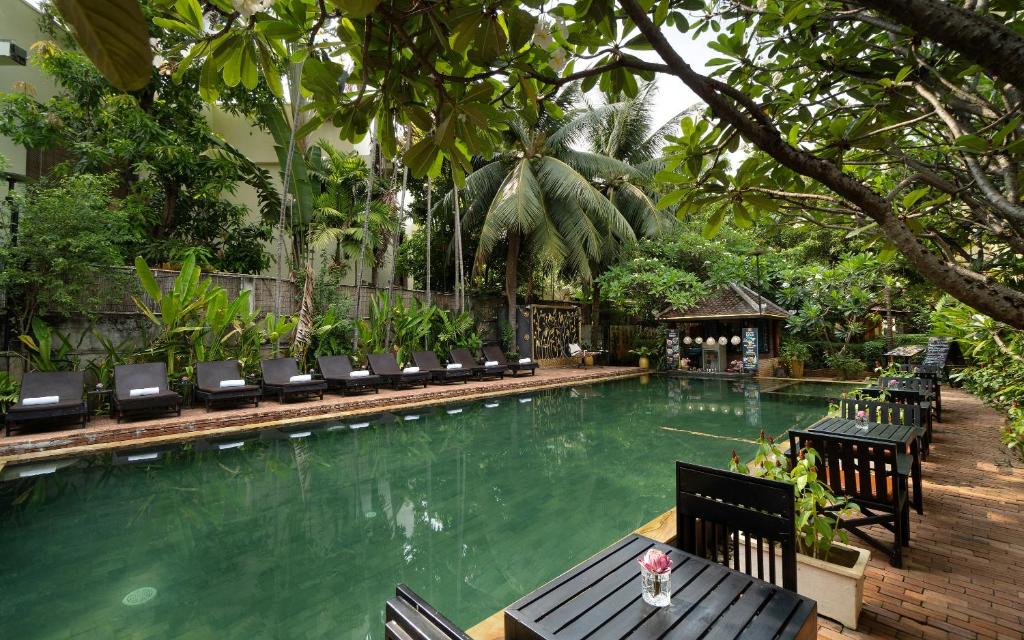 a swimming pool with chairs and a table in front of it at Home Indochine d'Angkor Hotel in Siem Reap