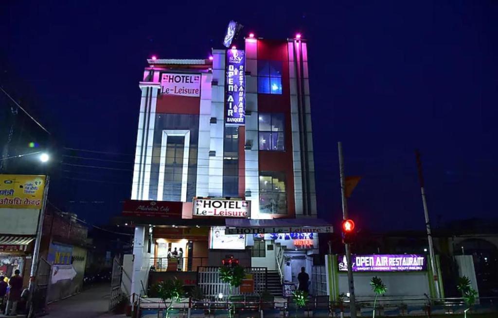 a hotel building with neon signs on it at night at Le-Leisure Hotel in Prayagraj