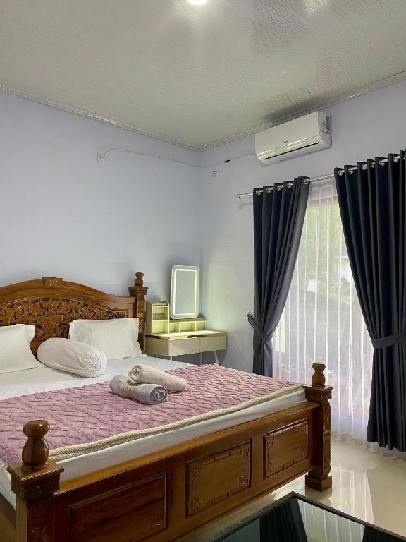 a bedroom with a bed with a purple comforter and a window at Sulis homestay in Kuta Lombok