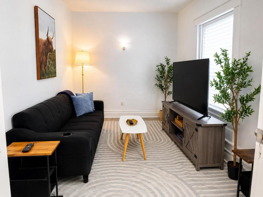 a living room with a black couch and a flat screen tv at Spacious Modern 2BR Apartment Sleeps 6 in Niagara Falls