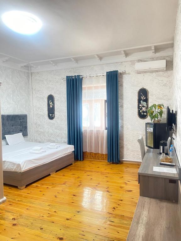 a bedroom with a bed and blue curtains and a wooden floor at GLOBUS Avenue Hotel in Yakkasaray