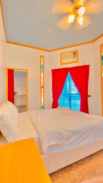a bedroom with a white bed and red curtains at Qurum Heights Hotel in Muscat