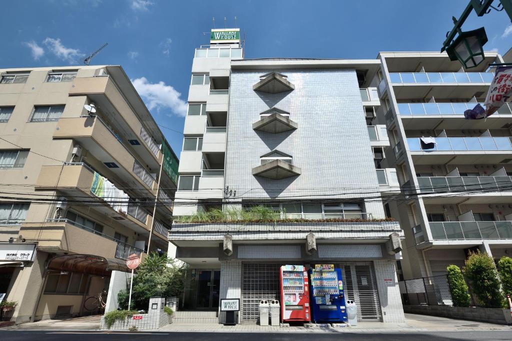 a tall white building with balconies on the side of it at Wallaby House in Kawaguchi