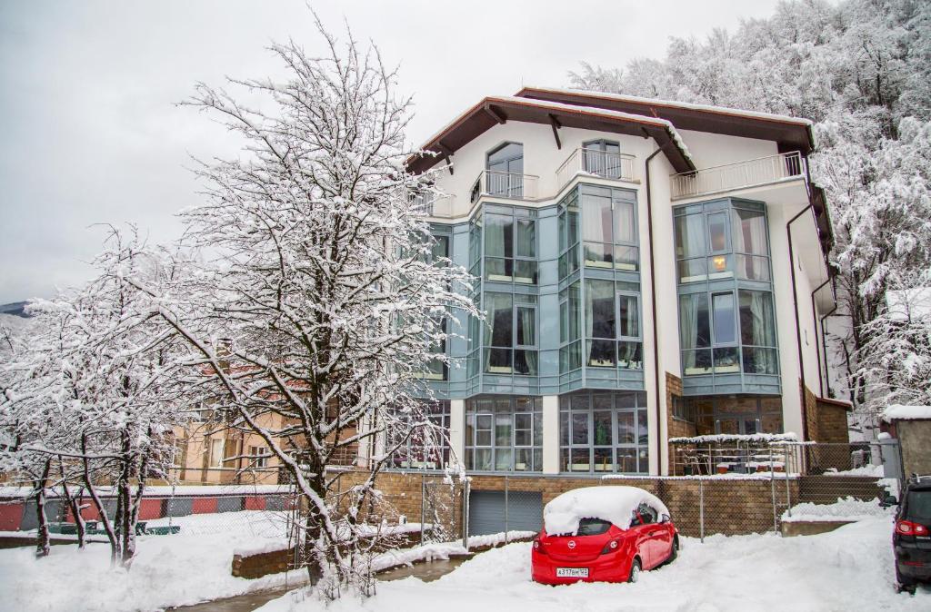 エストサドクにあるCrystal Hotelの雪に停められた赤い車を持つ家