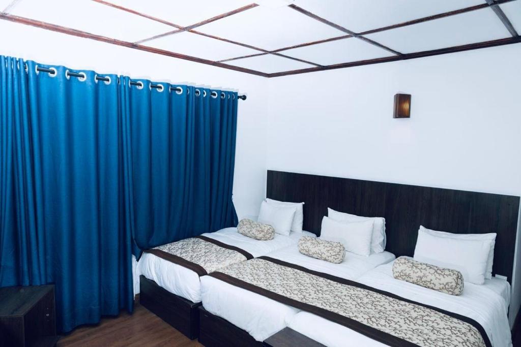 a bedroom with two beds with blue drapes at NAT CITY Hotel in Nuwara Eliya