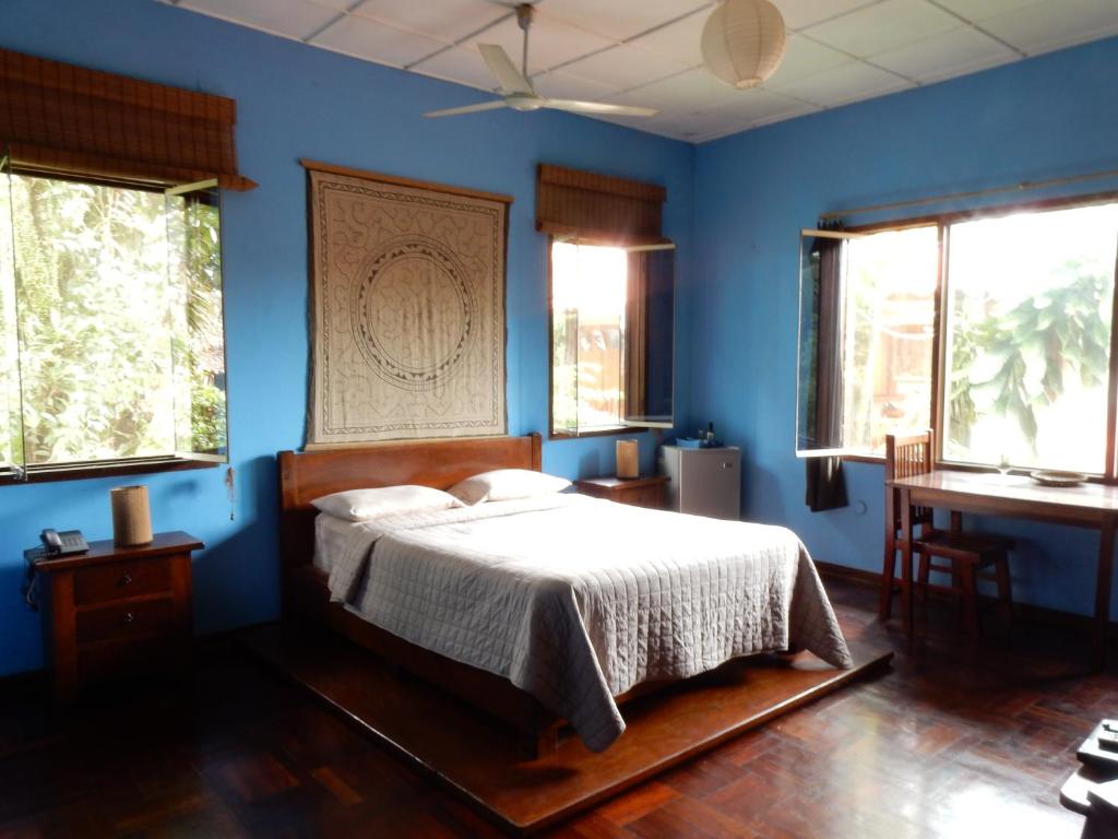 a bedroom with a bed with blue walls and windows at La Casa Fitzcarraldo in Iquitos