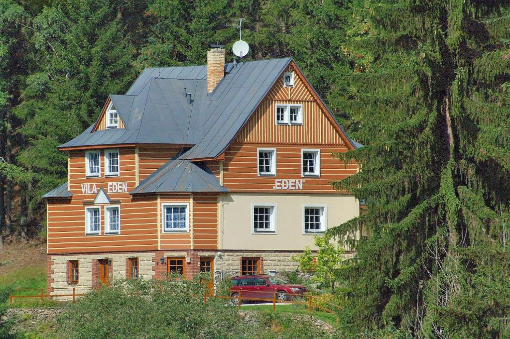 een groot houten huis met een auto ervoor bij Vila Eden in Pec pod Sněžkou