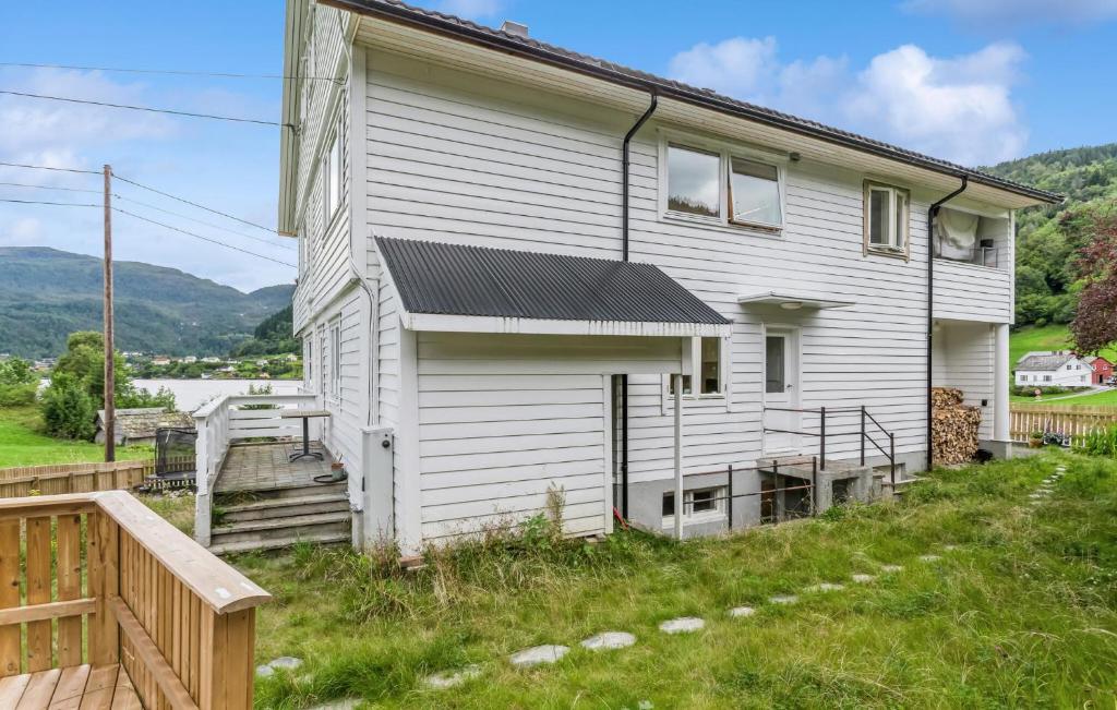 a white house with a porch and a wooden deck at Awesome Apartment In Strandebarm in Strandebarm