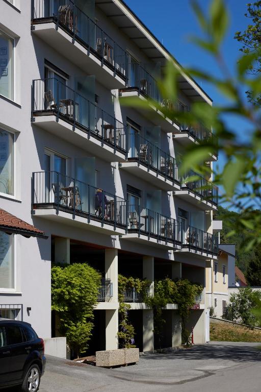 an apartment building with balconies and a car parked in front at I AM HOTELS Graz-Seiersberg in Graz