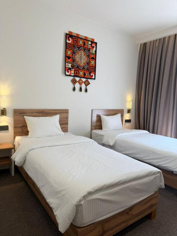 a bedroom with two beds and a picture on the wall at TES Hotel in Osh